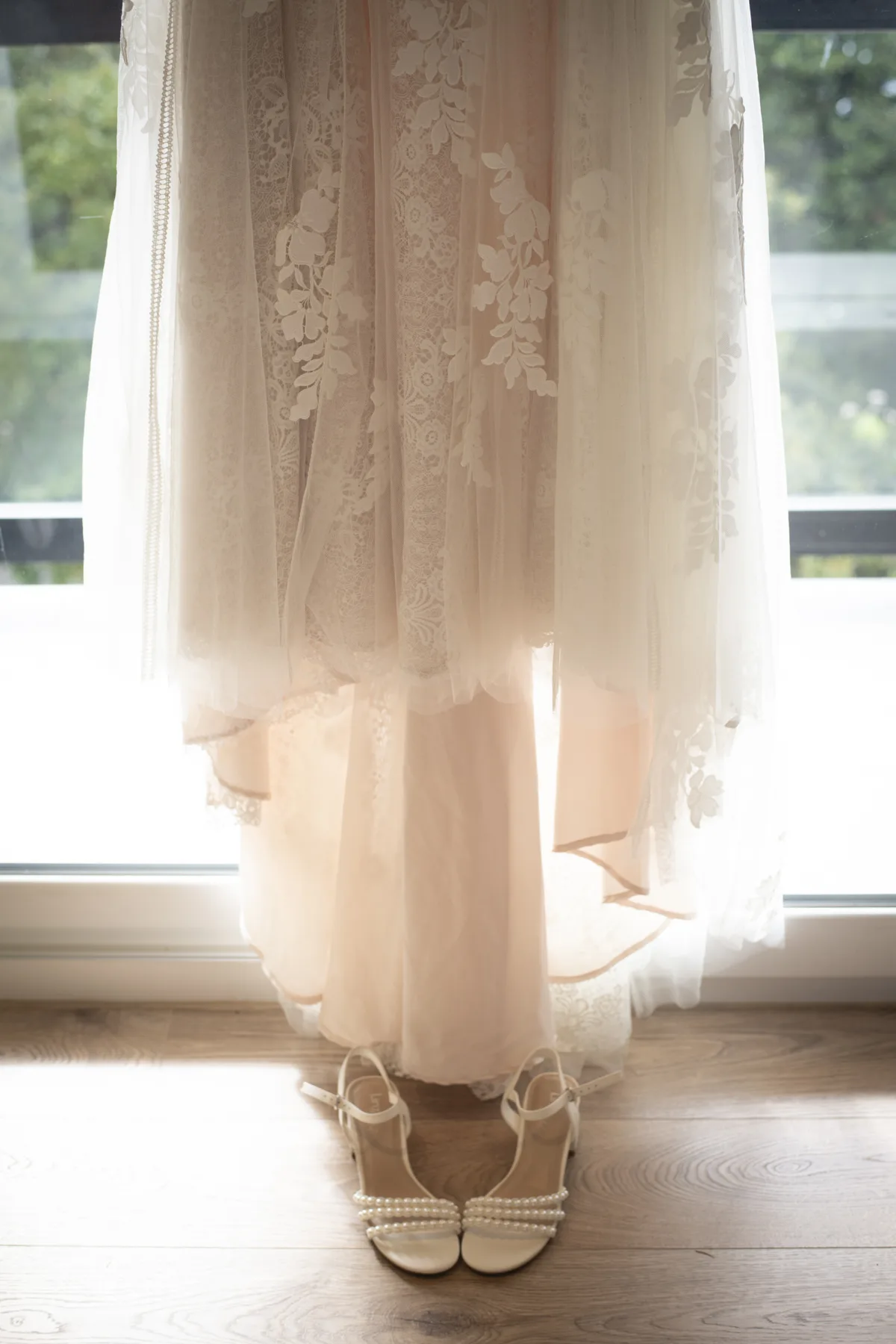 A wedding dress and shoes waiting in soft morning light