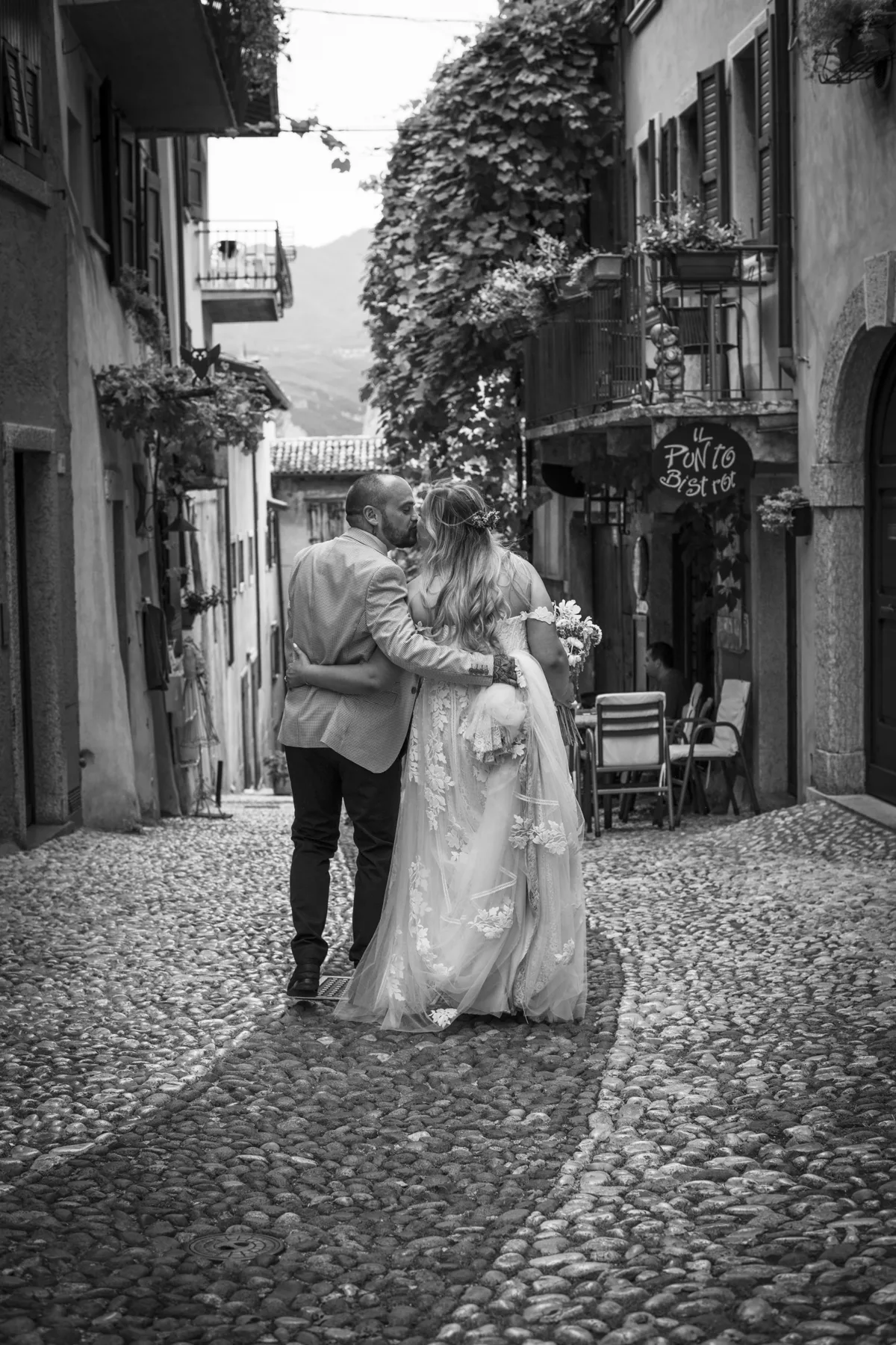 A black and white portrait of newlyweds in a village street