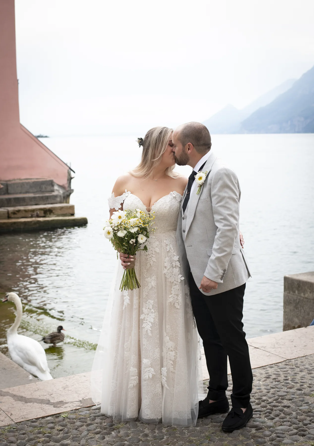 A newlywed couple sharing their first kiss by Lake Garda