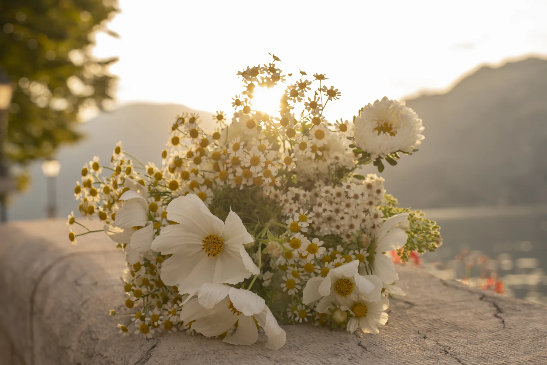 A wild bridal bouquet resting on a stone wall above Lake Garda