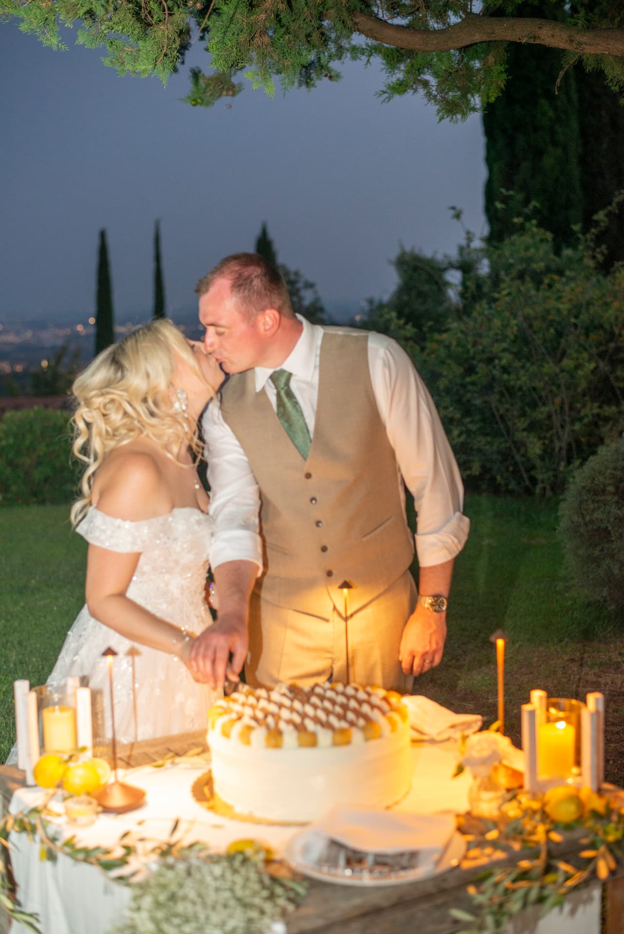 Claudia and Chris cutting their wedding cake by candlelight above Verona