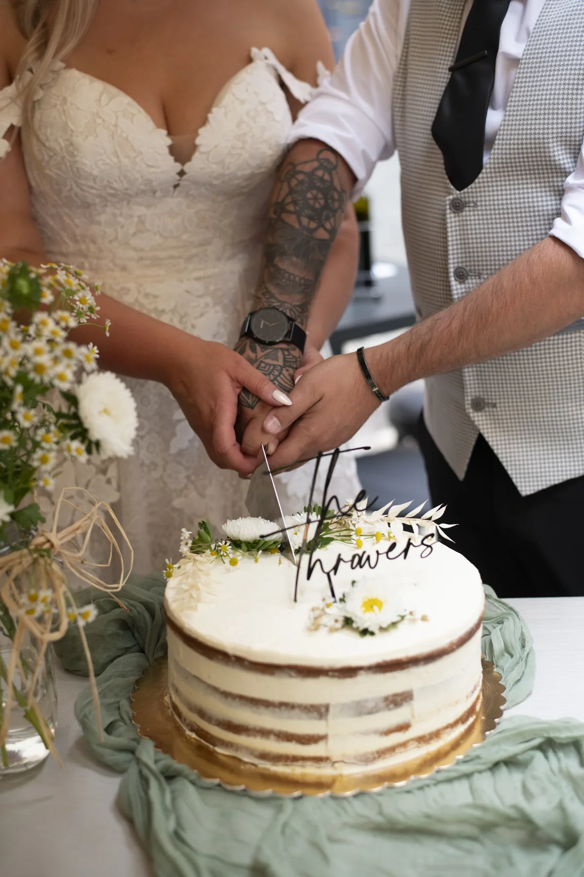 A newlywed couple cutting their naked wedding cake