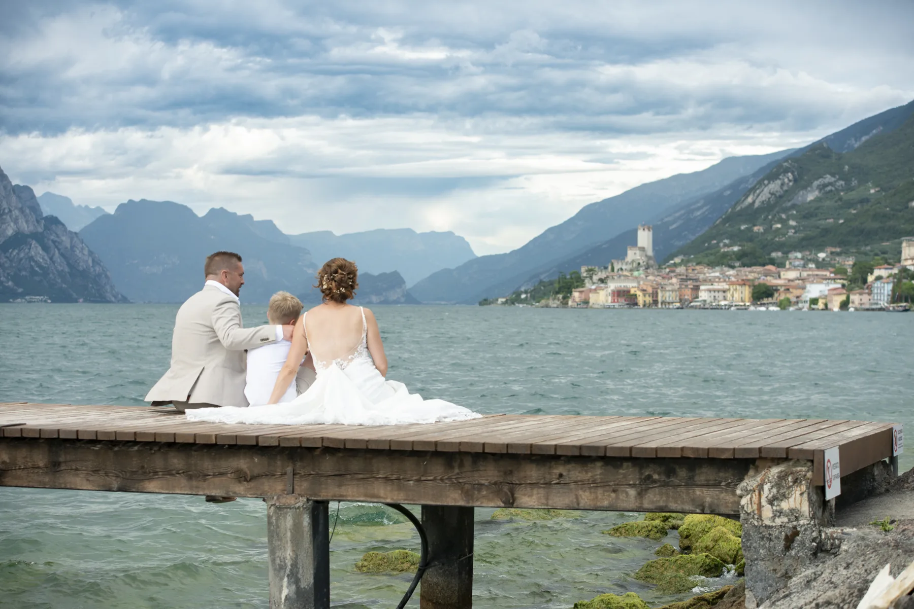 A couple sitting together on a jetty on Lake Garda