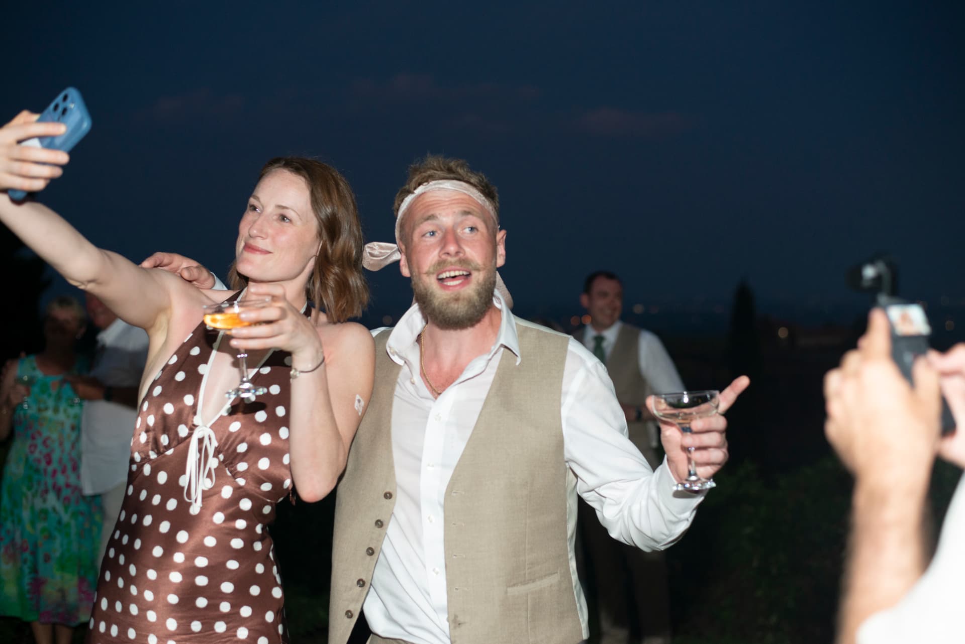 Guests celebrating with best man Joe, a tie around his head, late in the evening